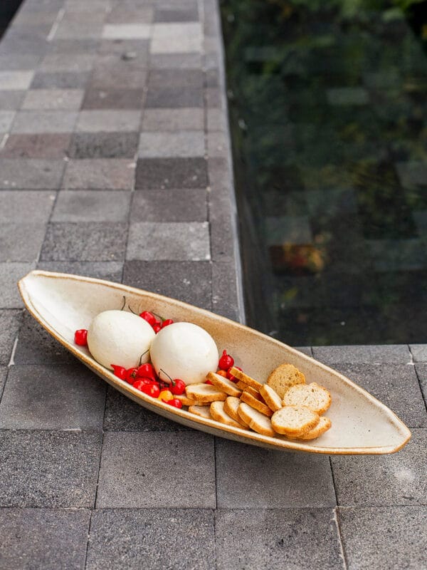 A canoa de cerâmica off da Danielle Raiola é uma peça de design autoral que transita com facilidade entre a decoração de interiores e a mesa posta. Com linhas orgânicas e acabamento refinado, ela une estética e multifuncionalidade em um único objeto.