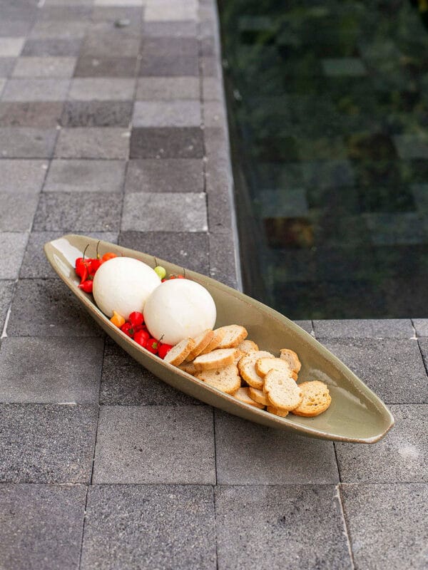 Canoa em cerâmica oliva. Com design sofisticado e formato versátil, é perfeita para decorar estantes, racks e mesas laterais, além de ser uma forma elegante de servir aperitivos, burratas e acompanhamentos.